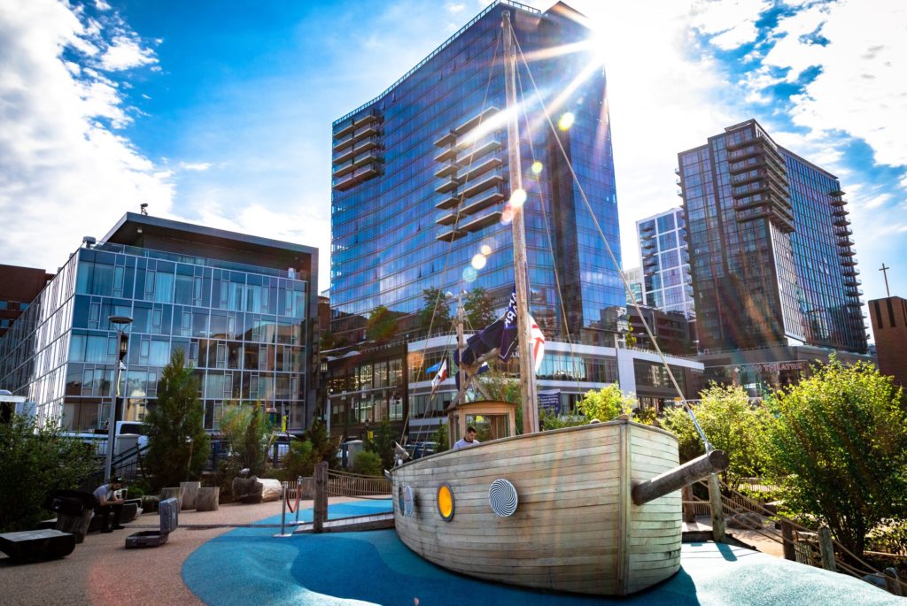 A play ship in Martins Park at the Smith Family Waterfront with tall buildings and glistening sun in the background.